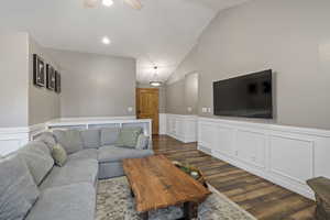 Living room with ceiling fan, dark hardwood / wood-style floors, and vaulted ceiling