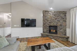Living room with vaulted ceiling, dark hardwood / wood-style floors, and a fireplace