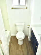 Full bath with vanity, baseboards, toilet, and wood finished floors