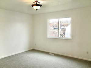 Spare room with carpet, visible vents, and baseboards