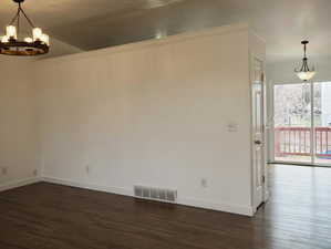Unfurnished room featuring visible vents, baseboards, a chandelier, and dark wood-style floors