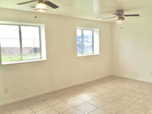 Spare room with visible vents, baseboards, a ceiling fan, and light tile patterned flooring
