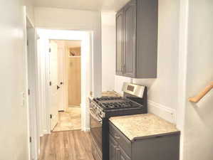 Kitchen featuring gray cabinets, light wood-style floors, stainless steel range with gas stovetop, and baseboards
