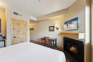 Bedroom with visible vents, baseboards, and a glass covered fireplace