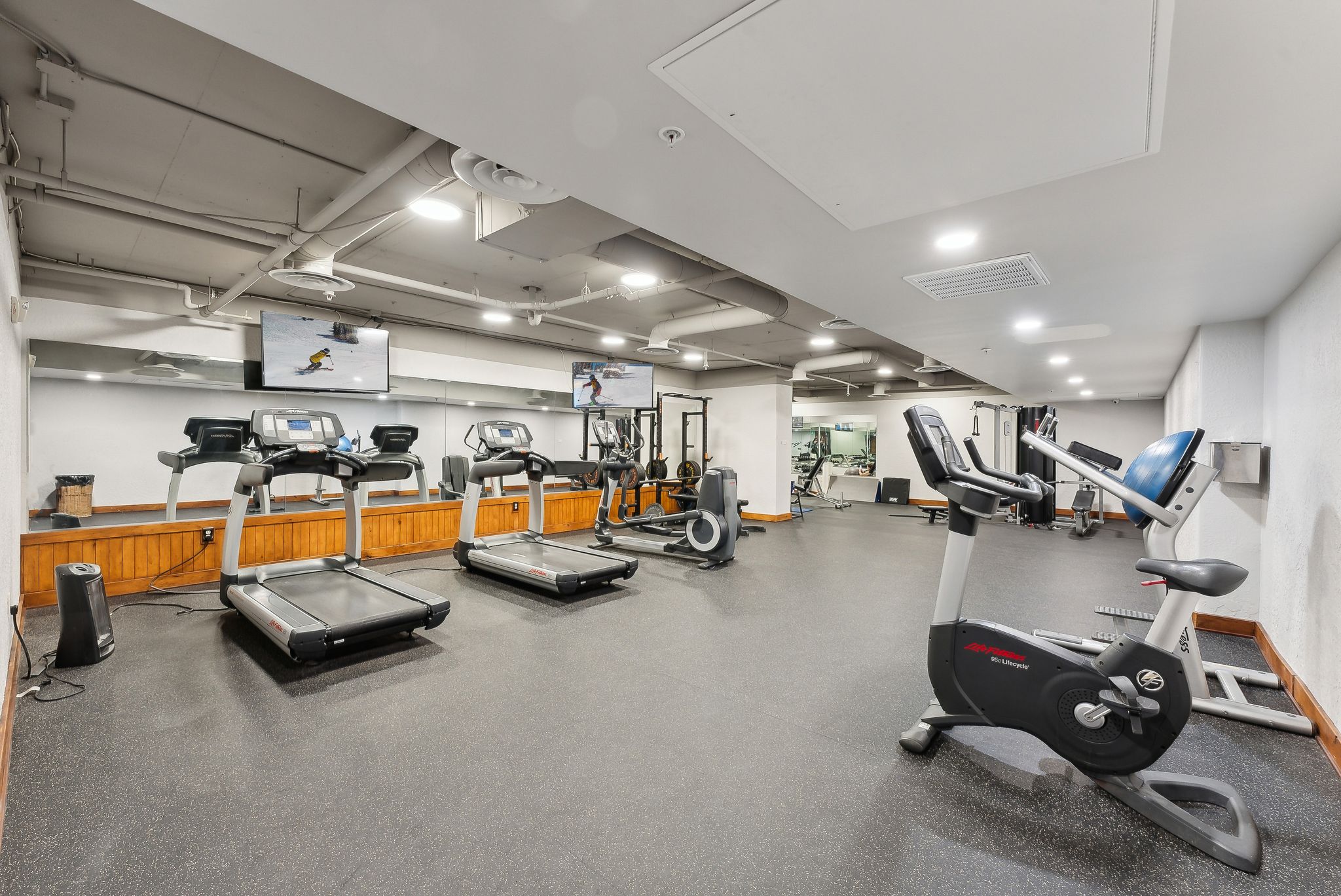 Dedicated fitness center featuring rubber flooring and mirrored walls