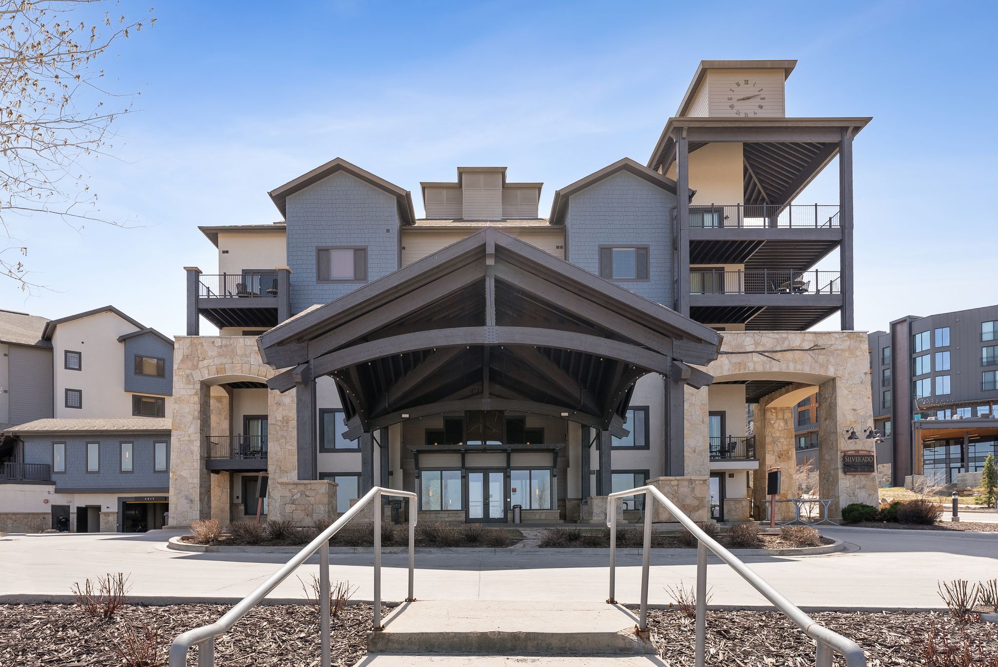 Multi-story building featuring a prominent covered entryway, stone accents, and multiple balconies