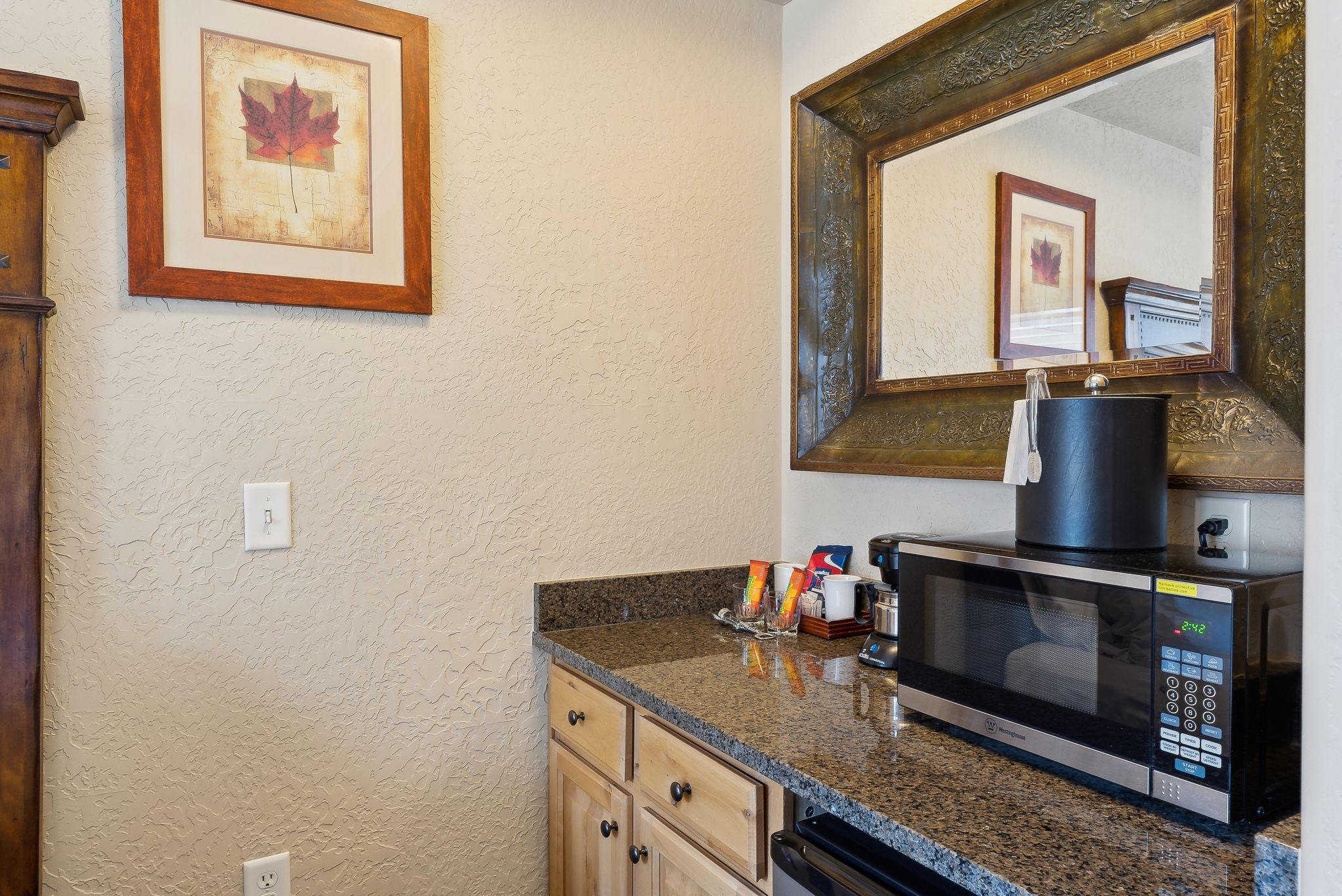 Built-in countertop with wood-finish cabinetry, a patterned stone surface, and an ornate framed mirror
