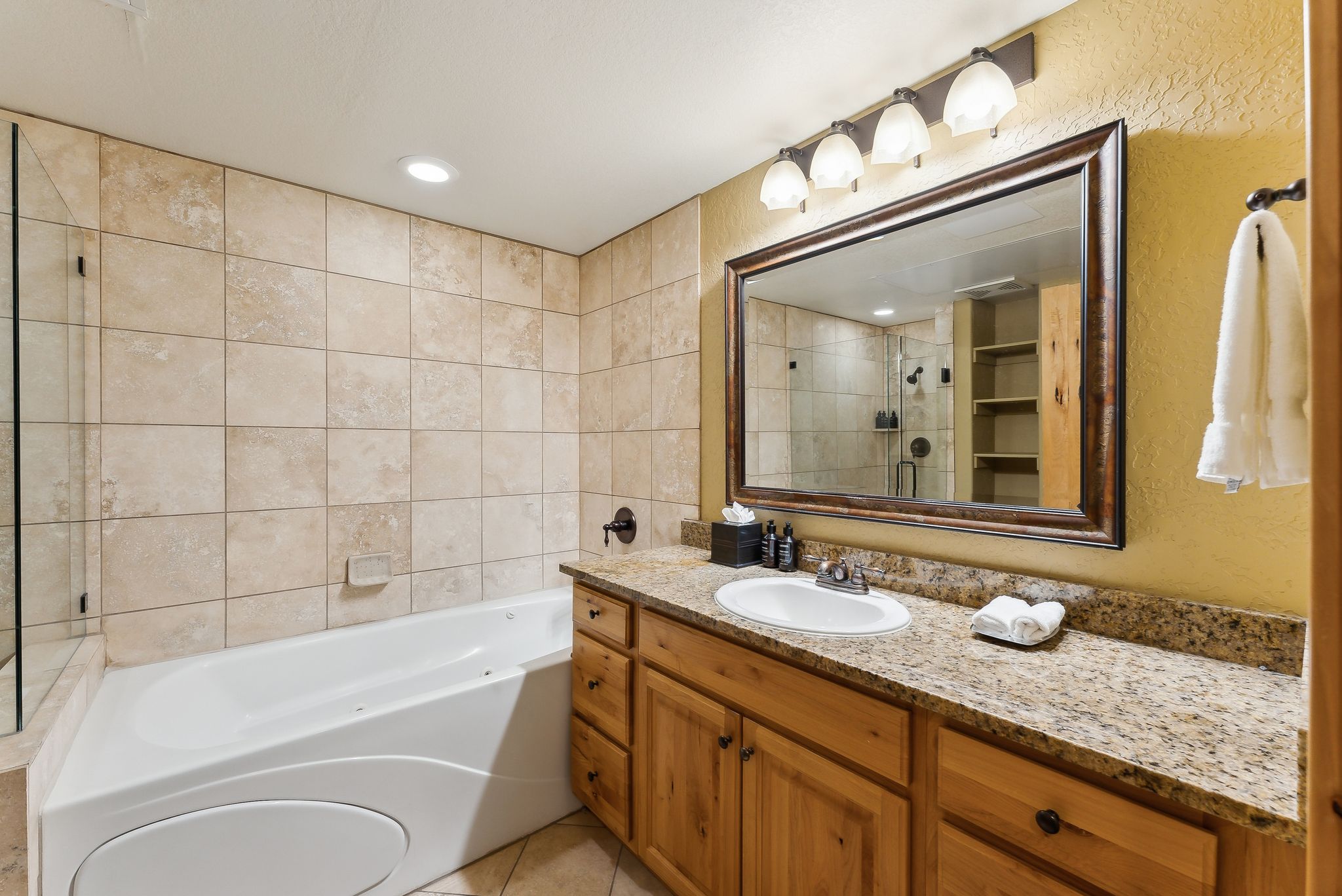 Bathroom featuring a dual-sink vanity with a granite countertop, wood cabinetry, and a framed mirror