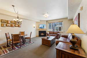Carpeted living area with a lit fireplace and an inviting chandelier