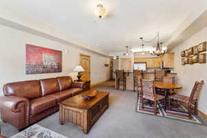 Carpeted living room featuring baseboards and a chandelier
