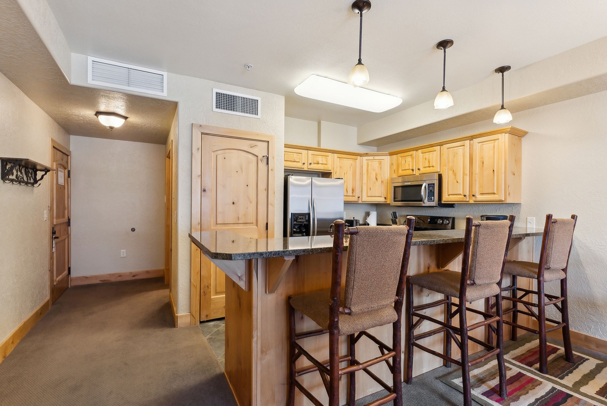 Kitchen featuring light wood cabinetry, stainless steel appliances, and a breakfast bar with stone-finish countertops