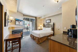 Carpeted bedroom with access to outside and a fireplace