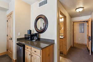 Kitchen with wine cooler, baseboards, visible vents, and dark stone countertops