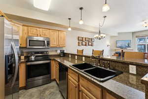 Kitchen with a notable chandelier, light brown cabinets, a sink, appliances with stainless steel finishes, and pendant lighting