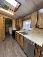 Kitchen with stainless steel dishwasher, washer / clothes dryer, gas range, a sink, and light countertops