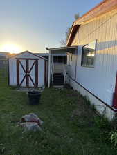 View of home's exterior featuring a storage shed, a lawn, and an outbuilding