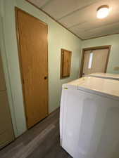 Laundry area with dark wood-type flooring, laundry area, and washing machine and dryer