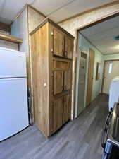 Kitchen featuring brown cabinetry, freestanding refrigerator, dark wood finished floors, and washer / clothes dryer