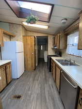Kitchen with light countertops, visible vents, appliances with stainless steel finishes, a sink, and wood finished floors