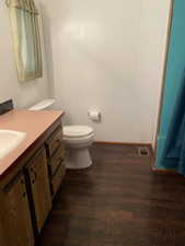Half bathroom featuring visible vents, toilet, vanity, and wood finished floors