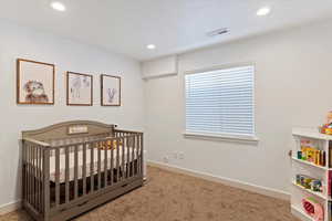 Bedroom featuring baseboards, recessed lighting, visible vents, a nursery area, and carpet