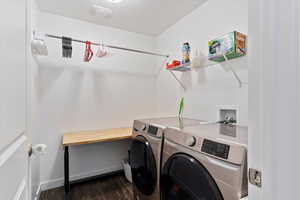 Laundry room featuring dark wood-type flooring, baseboards, washer and dryer, and laundry area