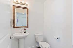 Bathroom featuring a sink, toilet, and baseboards
