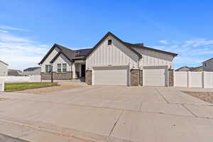 Modern inspired farmhouse featuring board and batten siding, driveway, stone siding, and a garage