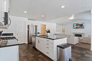 Kitchen with dark wood-type flooring, a sink, dark countertops, and stainless steel appliances
