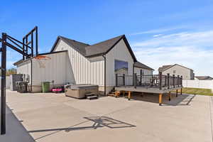Exterior space featuring board and batten siding, a wooden deck, fence, and a hot tub