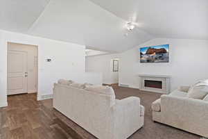 Living area with visible vents, baseboards, dark wood-style floors, and vaulted ceiling