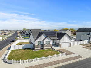 View of front of house featuring board and batten siding, roof mounted solar panels, a residential view, and a fenced front yard