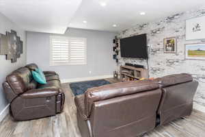Living area with recessed lighting, an accent wall, baseboards, and wood finished floors