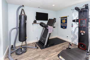 Exercise room with visible vents, baseboards, and wood finished floors