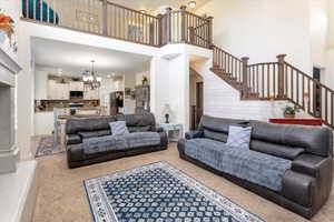 Living area featuring a chandelier, stairway, light carpet, and a high ceiling