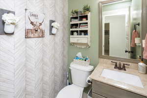 Bathroom with tiled shower, vanity, and toilet