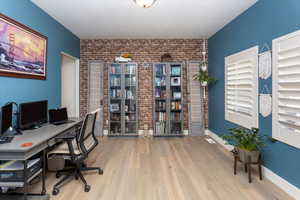 Office area featuring brick wall, an accent wall, and wood finished floors