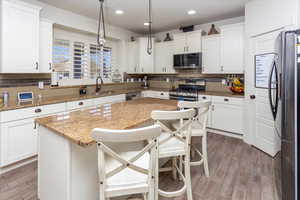 Kitchen featuring stainless steel appliances, a center island, a sink, and decorative backsplash
