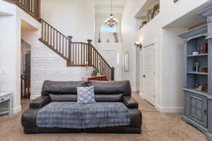 Living area featuring a chandelier, a towering ceiling, baseboards, and stairs