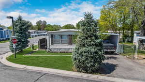 View of front of house with a front lawn, driveway, a carport, and fence