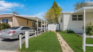 View of property exterior with a carport, a lawn, an outdoor structure, and a shed
