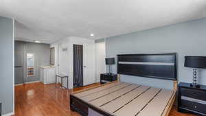 Bedroom with baseboards, wood finished floors, and a textured ceiling