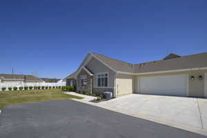 Single story home with a front lawn, a garage, driveway, and stucco siding