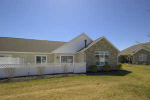 Single story home featuring stone siding, a front yard, and fence private yard