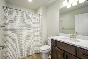 Bathroom with visible vents, toilet, vanity, and wood finished floors