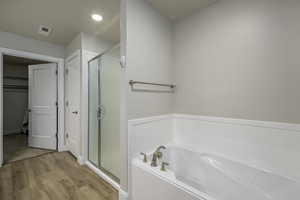 Bathroom with visible vents, a bath, recessed lighting, a shower stall, and wood finished floors