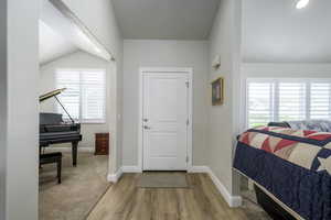 Foyer entrance with baseboards, vaulted ceiling, and wood finished floors