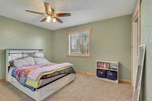 Carpeted bedroom featuring baseboards and ceiling fan