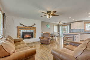Living area featuring recessed lighting, light wood finished floors, a fireplace, and ceiling fan