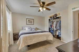 Carpeted bedroom with a closet, ceiling fan, and baseboards